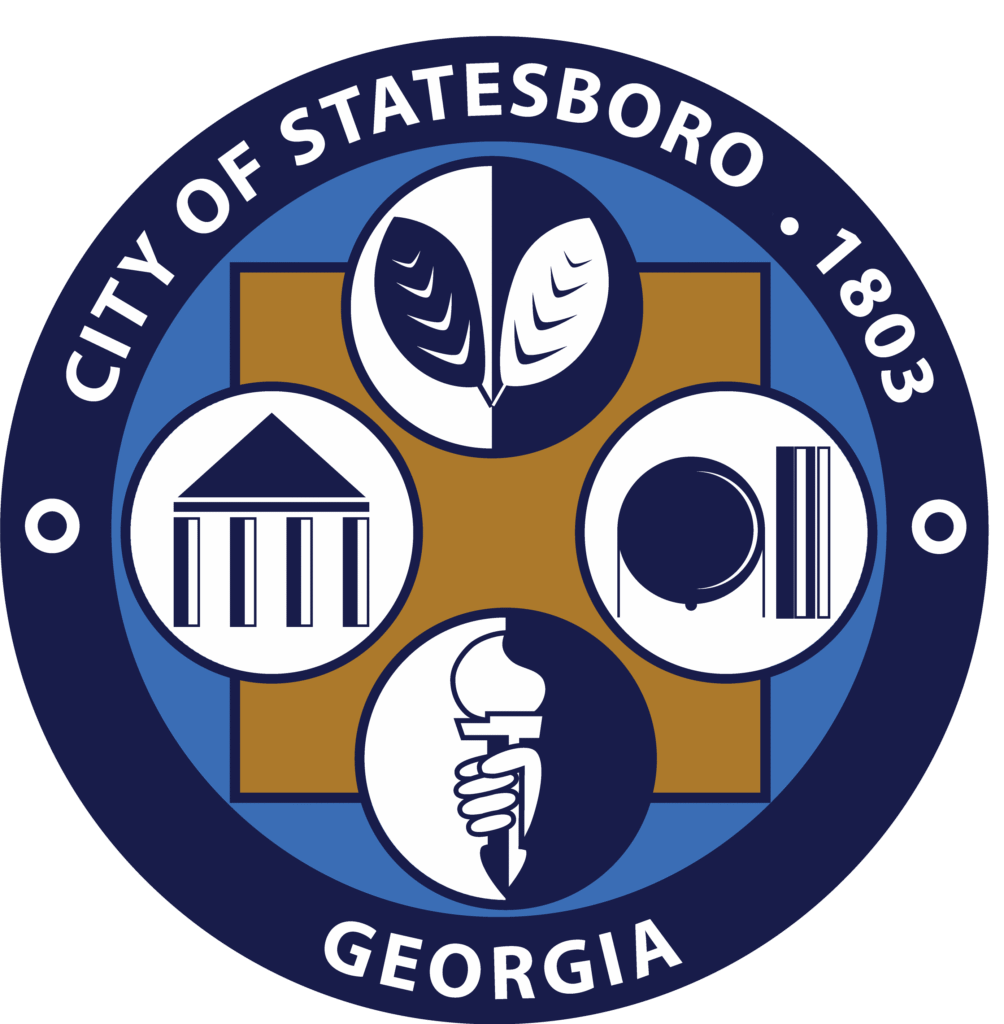 Official logo of the City of Statesboro, Georgia. The circular emblem features the text “CITY OF STATESBORO • 1803 • GEORGIA” around the outer edge. Inside the circle are four symbolic icons representing the city's values and services: agriculture (leaves), government (a classical building), communication and technology (a speech bubble and barcode-like lines), and education or enlightenment (a hand holding a torch). The symbols are arranged around a central square with a blue and gold color scheme.