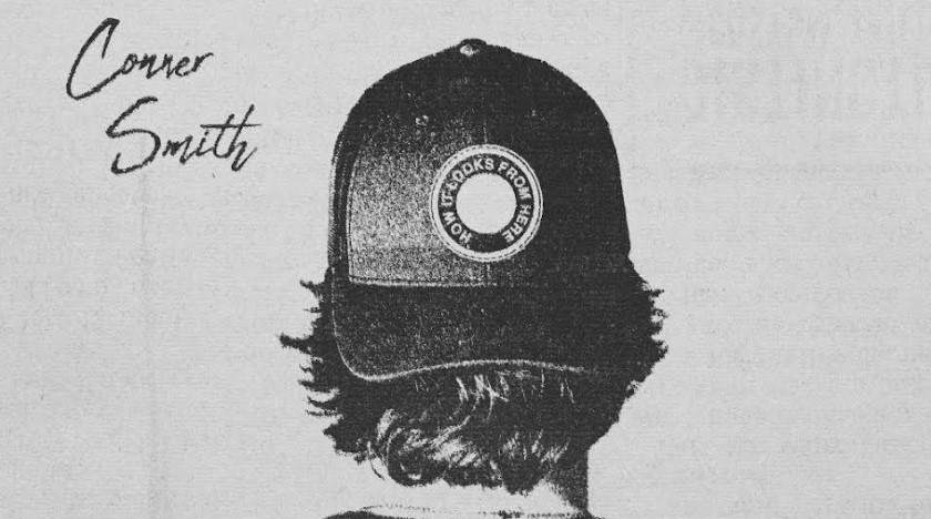 A black and white image of a person seen from behind, wearing a baseball cap with long hair curling out beneath it. The cap has a circular patch that reads "HOW IT LOOKS FROM HERE." The name "Conner Smith" is written in stylized cursive on the upper left of the image.