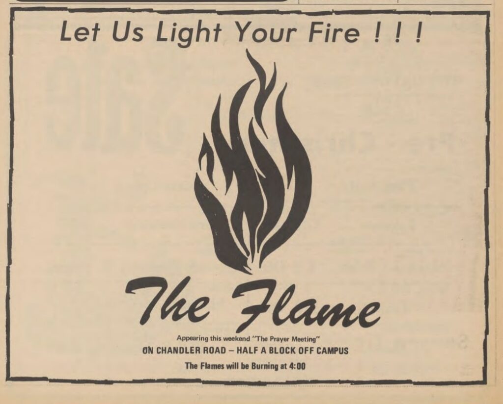 A vintage black-and-white flyer featuring the text 'Let Us Light Your Fire!!!' at the top, accompanied by an abstract flame graphic in the center. Below the graphic, the words 'The Flame' are written in a stylized script. Additional details include the location, 'On Chandler Road - Half a Block Off Campus,' and the event note, 'Appearing this weekend: The Prayer Meeting.' The tagline concludes with, 'The Flames will be Burning at 4:00,' creating a promotional and evocative design.