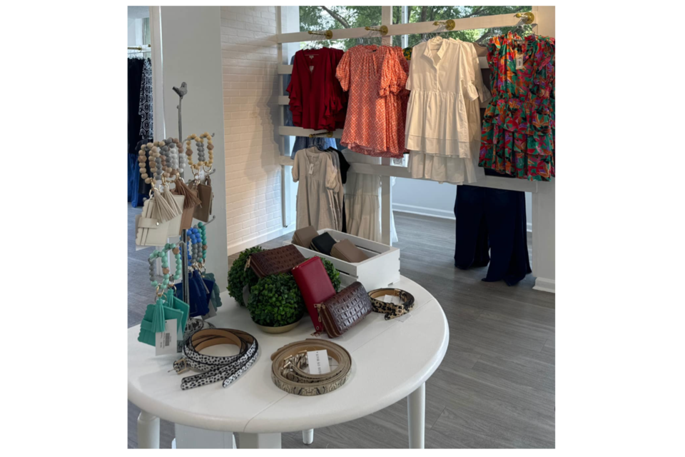 Accessories and clothing display inside Mirror On Main Boutique in Statesboro, Georgia featuring colorful dresses, handbags, belts, and jewelry arranged on a retail table.