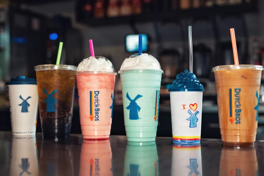 Assorted Dutch Bros Coffee drinks lined up on a counter, including iced coffee, blended drinks, and a colorful kids drink.